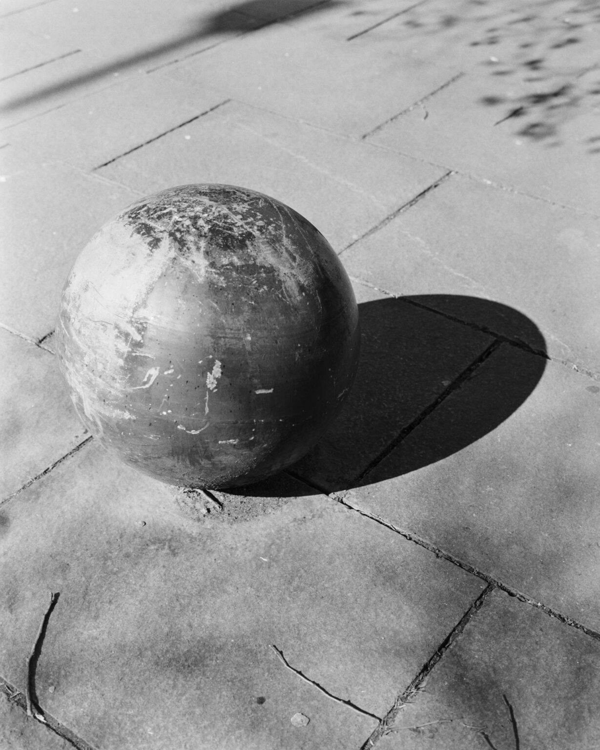 Black and white photograph of a strange looking concrete ball, with a shadow