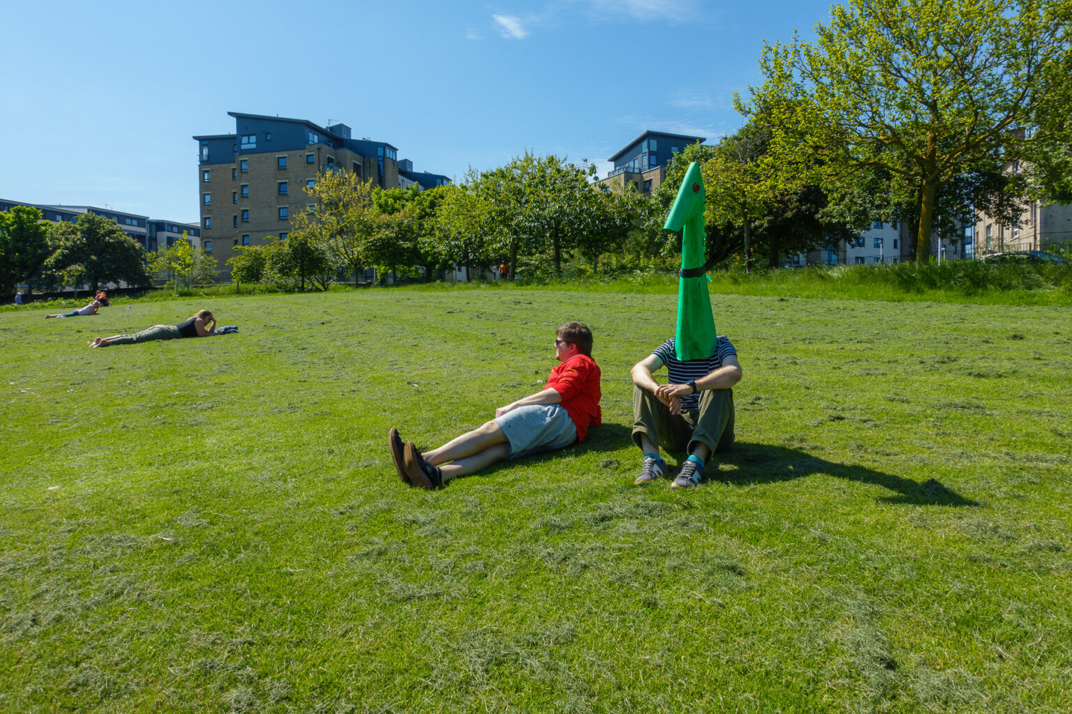 Wojtek as Nessie in the park, sitting next to a person who ignores him