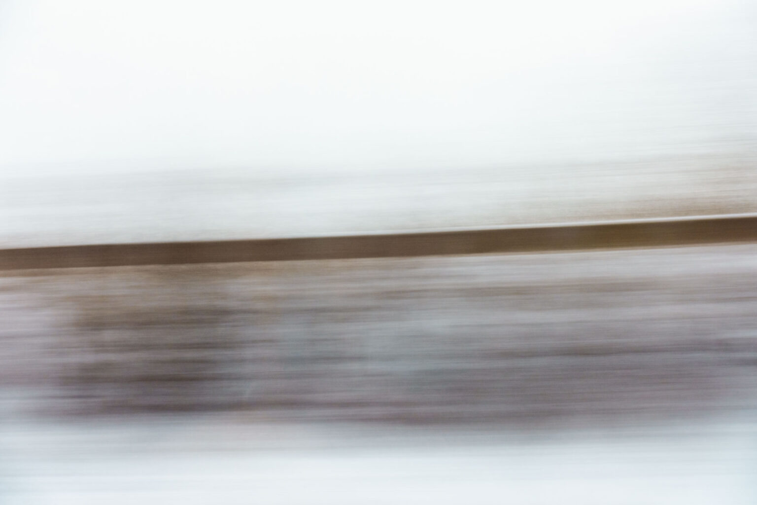 A blurry landscape image shot through a window on a moving train