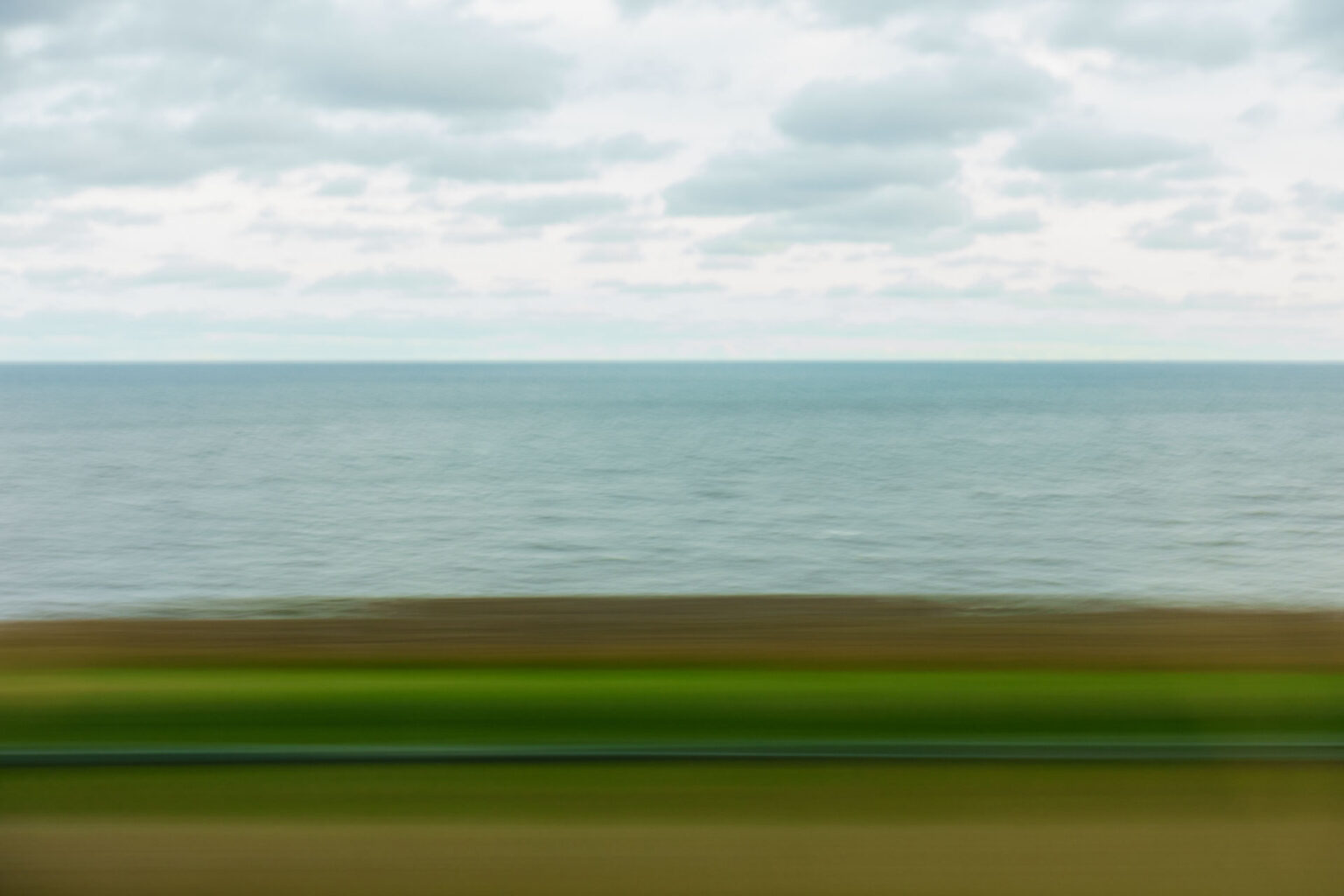 A blurry landscape image shot through a window on a moving train