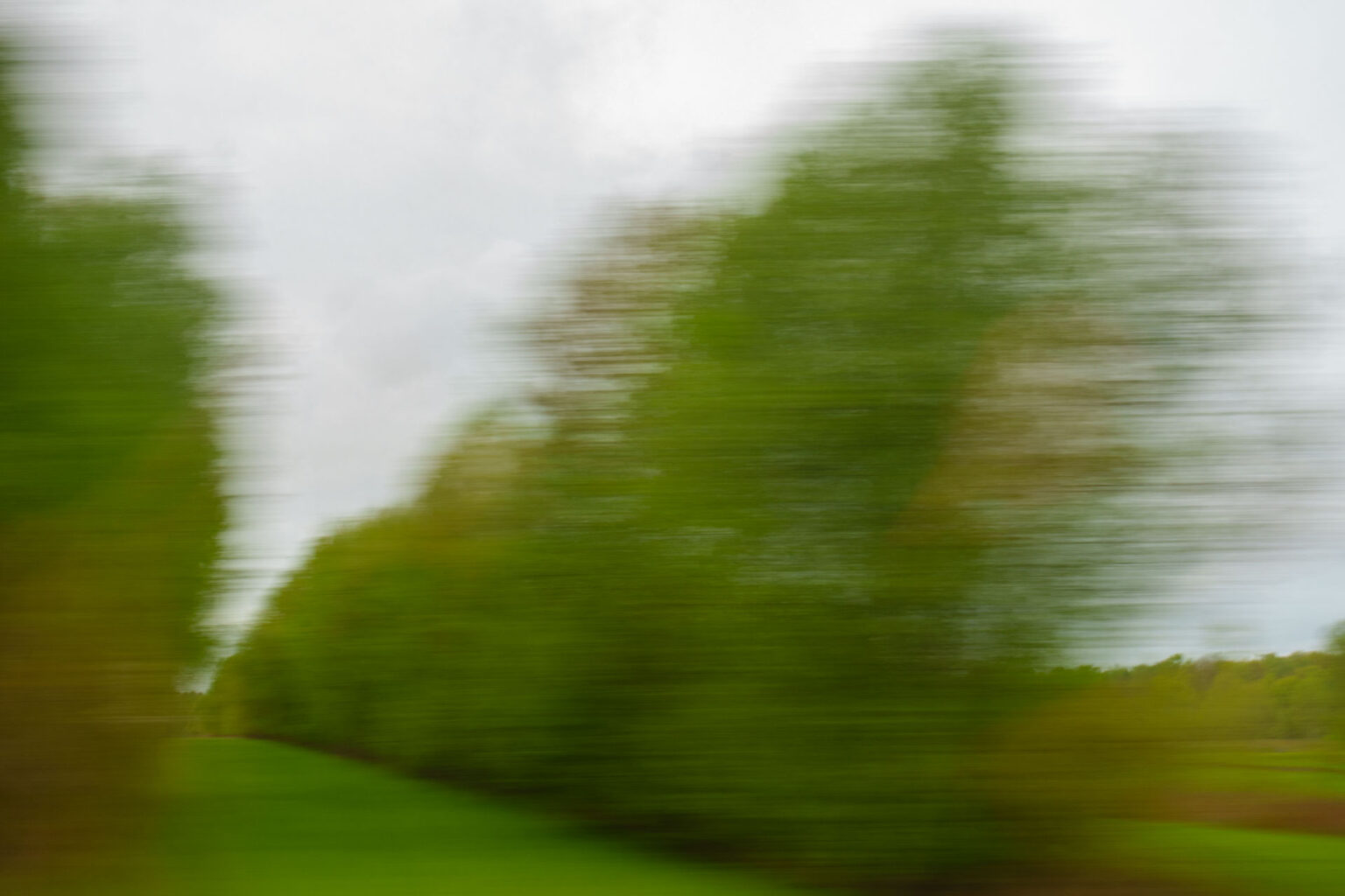 A blurry landscape image shot through a window on a moving train