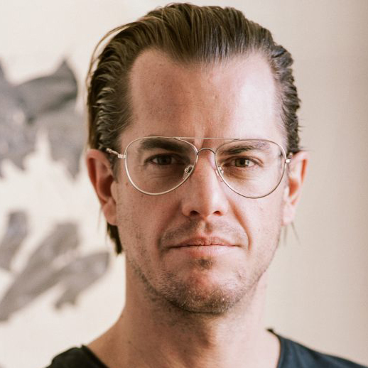 Portrait of Jonathan Freemantle with one of his paintings in the background.