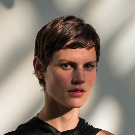 Portrait of Saskia de Brauw, an international fashion model, in a black dress on a sunlit wall.